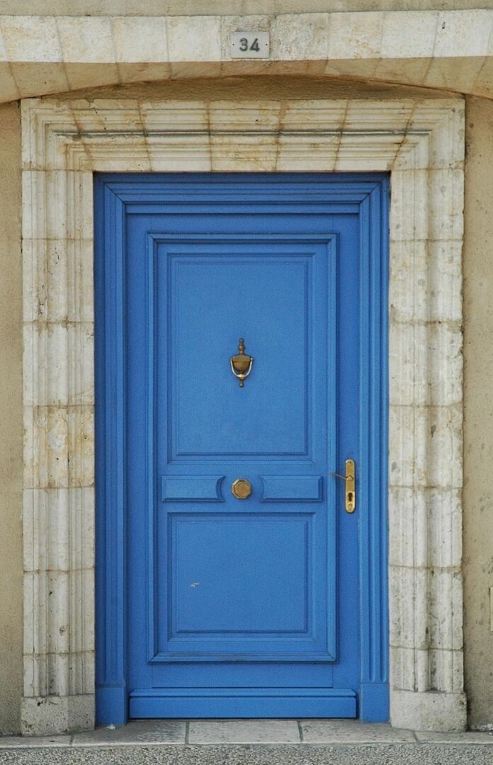 A blue door with a gold handle and a stone surround.